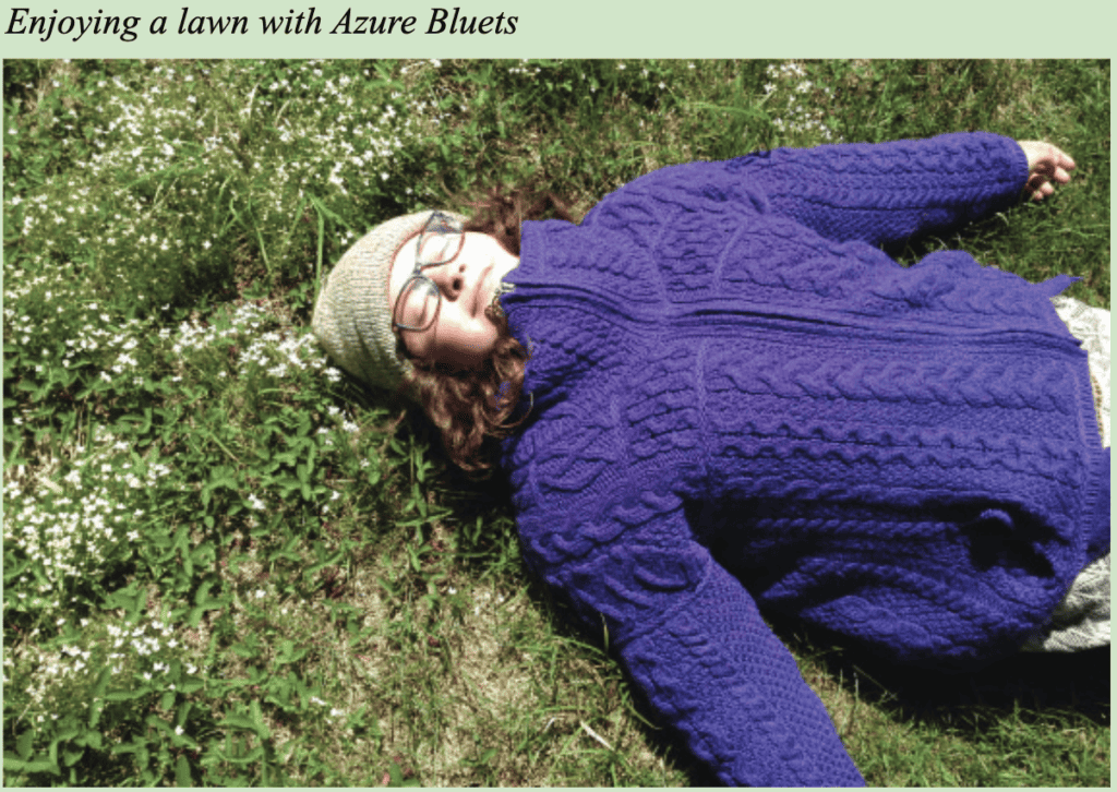 Girl smiling in purple sweater lying on the ground. Text reads "enjoying a lawn with Azure Bluets".
